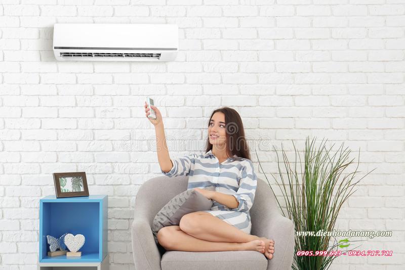 Woman Switching on Air Conditioner while Sitting on Sofa Near White Wall Stock Photo - Image of cooler, happy: 120064784